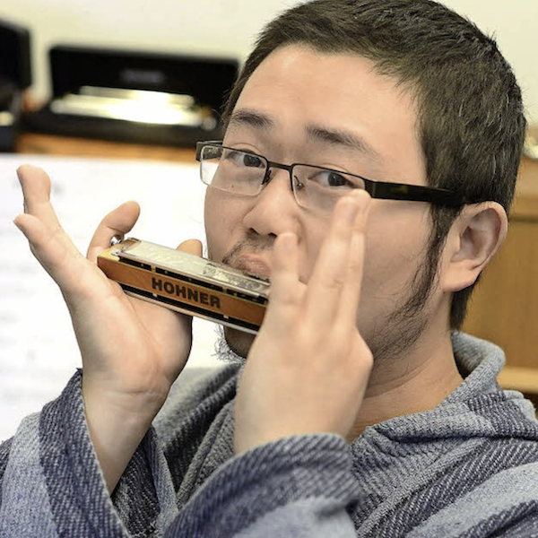 Tian Long Li spielt eine Hohner- Mundharmonika